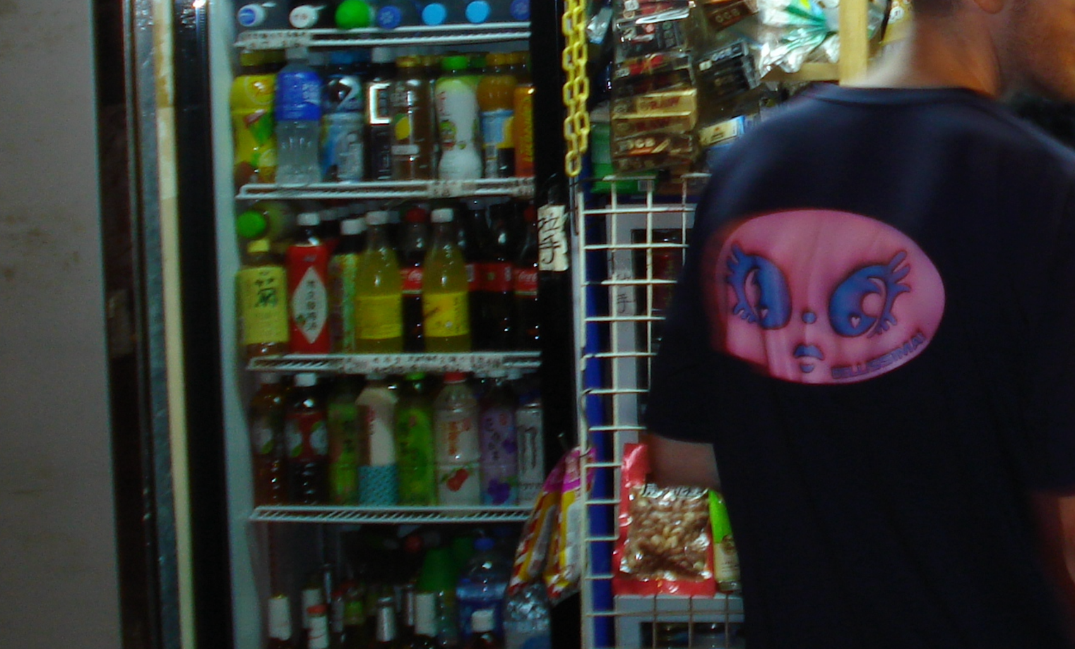 BELLISSIMA! 'HAVE A BELLISSIMA DAY!' navy tee with a pink graphic 'Gigi' back-print next to a vending machine in stocked with various drinks and snacks in Hong Kong.